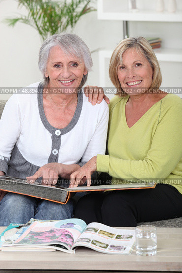 Mother and daughter looking through photo album. Стоковое фото, агентство Ingram Publishing / Фотобанк Лори