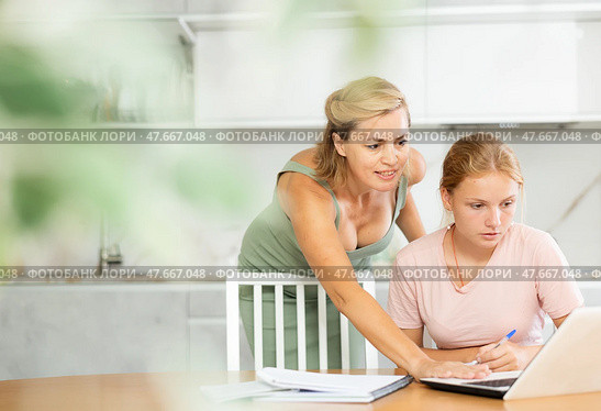 Mother assisting teenage daughter doing school assignment at home. Стоковое фото, фотограф Яков Филимонов / Фотобанк Лори
