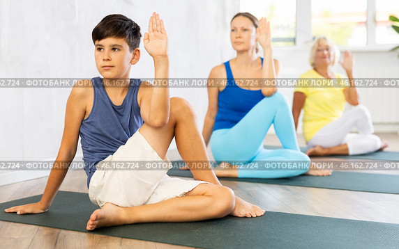Mother, grandmother and adolescence son do exercise lord of fish, Ardha Matsyedrasana. Стоковое фото, фотограф Яков Филимонов / Фотобанк Лори