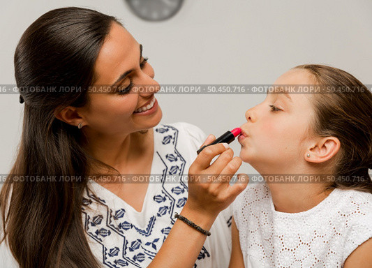 Mother playing with her daughter applying lipstick. Стоковое фото, агентство Ingram Publishing / Фотобанк Лори