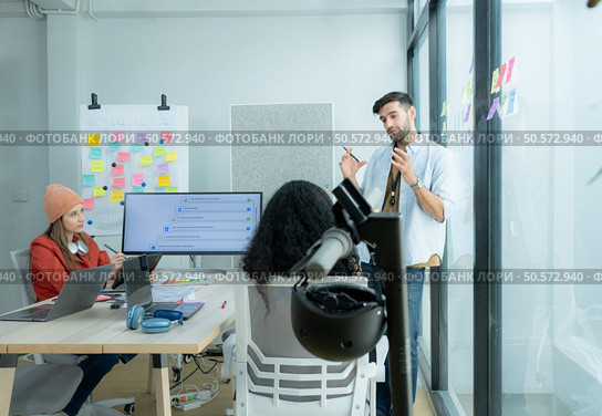 Multiethnic startup business team on meeting in modern bright office interior brainstorming, working on laptop and tablet computer. Стоковое фото, агентство Ingram Publishing / Фотобанк Лори
