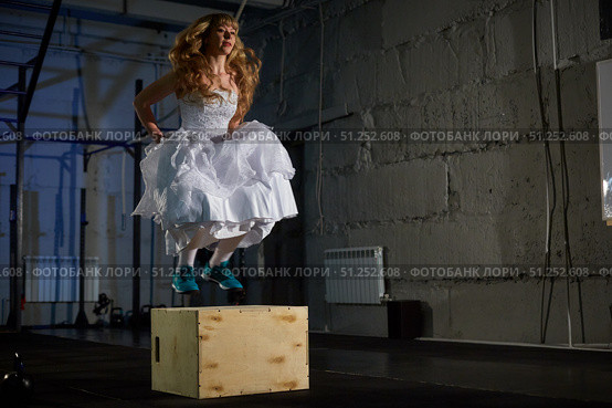 muscular bride in a wedding dress doing exercises on a wooden box in the gym. Стоковое фото, фотограф Арзюков Вадим Николаевич / Фотобанк Лори