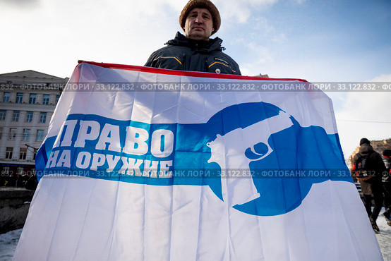 Мужчина держит баннер с надписью "Право на оружие" и изображением пистолета на митинге "За проведение референдума по поправкам в Конституцию и смену курса развития страны!" на Суворовской площади в городе Москве, Россия (2020 год). Редакционное фото, фотограф Николай Винокуров / Фотобанк Лори