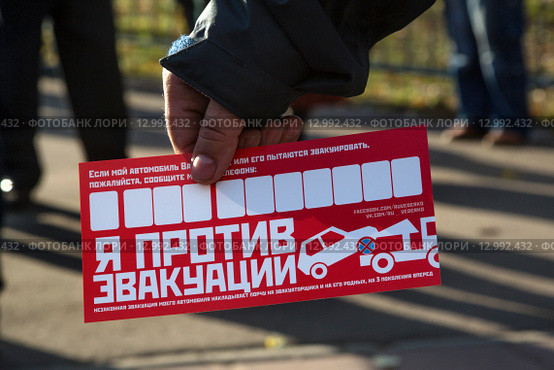 Мужчина держит красный стикер движения "Синие ведерки" для автовладельцев с надписью "Я против эвакуации" (2015 год). Редакционное фото, фотограф Николай Винокуров / Фотобанк Лори