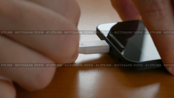Мужчина подключает USB-кабель к смартфону. Стоковое видео, видеограф Садовский Анатолий / Фотобанк Лори