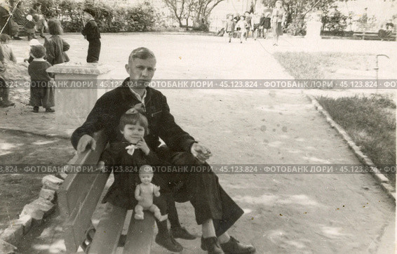 Мужчина с маленькой девочкой сидят на скамейке в парке. 1950-е годы. Стоковое фото, фотограф Retro / Фотобанк Лори