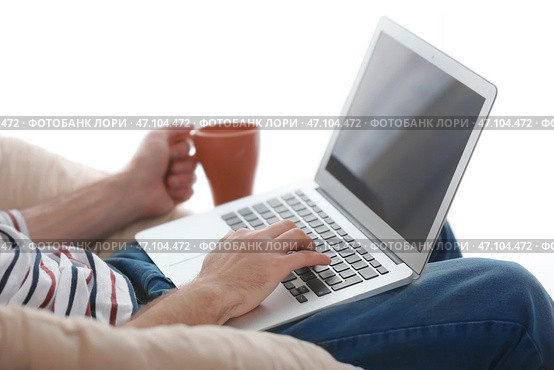 Мужской фрилансер пьет чай во время работы с ноутбуком в домашнем офисе. Стоковое фото, фотограф Pixel_shot / Фотобанк Лори