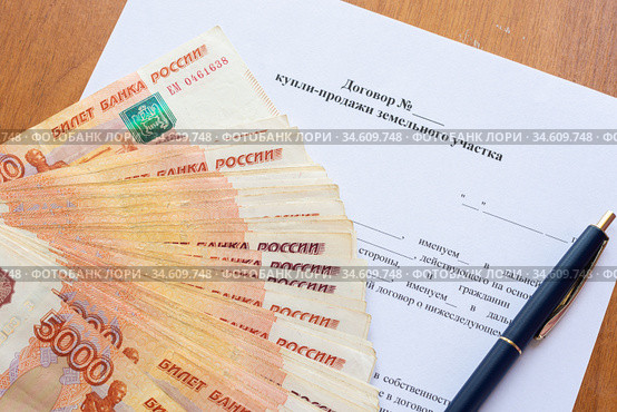 На договоре купли продажи земельного участка лежит пачка денег разложенных веером и ручка. Стоковое фото, фотограф Иванов Алексей / Фотобанк Лори