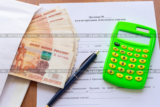 На столе лежит договор купли продажи земельного участка, пачка денег в конверте, ручка и калькулятор. Стоковое фото, фотограф Иванов Алексей / Фотобанк Лори