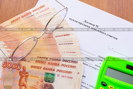 На столе лежит договор купли продажи земельного участка, пачка денег, калькулятор и очки. Стоковое фото, фотограф Иванов Алексей / Фотобанк Лори