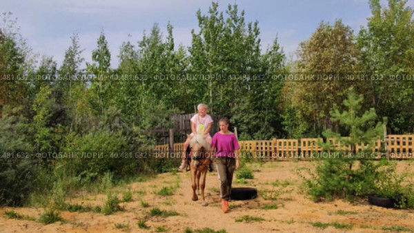 На улице в прекрасный теплый день девочка катается на лошади. Outside on a beautiful warm day, a girl rides a horse. Редакционное видео, видеограф Мария / Фотобанк Лори