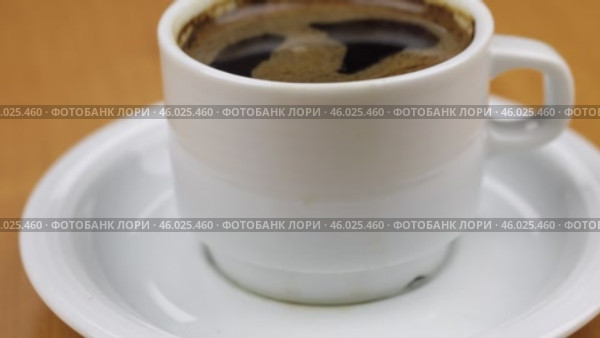На видео белая чашка с кофе на столе. Снимок с тележки. Крупный план. Небольшая глубина резкости. Стоковое видео, видеограф Александр Собко / Фотобанк Лори
