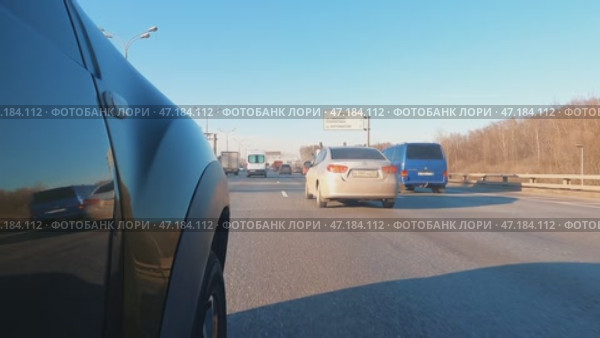 На видео видна правая сторона зеленого автомобиля, едущего по городскому шоссе в солнечный день. Транспортное средство движется на высокой скорости, обгоняя другие автомобили. Стоковое видео, видеограф Ярославский Максим / Фотобанк Лори