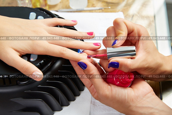 Nails painting with UV dry lamp in blue light woman hands at nail salon. Стоковое фото, агентство Ingram Publishing / Фотобанк Лори