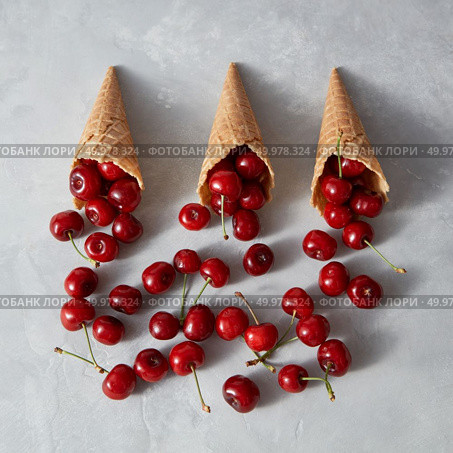 Natural freshly picked fruits cherries in waffle cones for homemade cakes on a gray background with place for text. Organic vegetarian raw eating.. Summer fresh organic fruits pattern - cherry in a wafer cones on a gray stone background. Стоковое фото, агентство Ingram Publishing / Фотобанк Лори