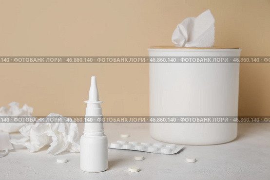 Назальные капли с таблетками и коробкой для салфеток на столе возле бежевой стены. Концепция аллергии. Стоковое фото, фотограф Pixel_shot / Фотобанк Лори