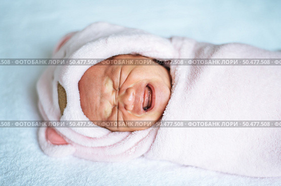Newborn baby wrapped in a soft pink blanket and crying. Стоковое фото, агентство Ingram Publishing / Фотобанк Лори