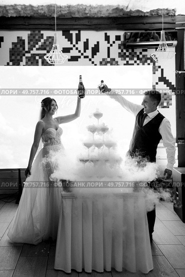newlyweds at a banquet pour champagne into a pile of glasses for guests. Стоковое фото, агентство Ingram Publishing / Фотобанк Лори