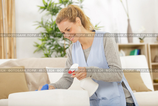 nice hard working woman spraying cleansing agent on the cushion. Стоковое фото, агентство Ingram Publishing / Фотобанк Лори