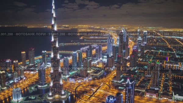 Nighttime aerial panorama revealing Dubai's luminous skyline, glowing Burj Khalifa towering over radiant urban landscape, capturing architectural magnificence and metropolitan brilliance. Стоковое AI-видео, аниматор Данил Руденко / Фотобанк Лори
