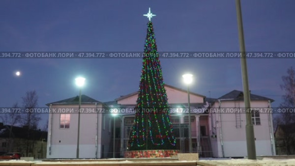Nikolskoye, Leningrad region, Russia 01.19.25: town square, towering Christmas tree decorated with colorful lights stands tall, snow covers ground under beautiful dusk sky, creating festive atmosphere (2017 год). Редакционное видео, видеограф Юлия Петровская / Фотобанк Лори