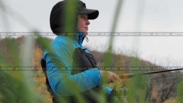Nizhny Novgorod, Russia, Oka River, 10.20.2023. Fishing. Fisherman woman with fishing rod on river bank in autumn. Spinning rod with reel, string and lure. High quality 4k footage Нижний Новгород, Россия, река Ока, 20.10.2023. Рыбная ловля. Женщина-рыбак с удочкой на берегу реки осенью. Спиннинговое удилище с катушкой, бечевкой и приманкой. Высококачественный видеоматериал в формате 4k. Редакционное видео, видеограф Egor Sarantstv / Фотобанк Лори