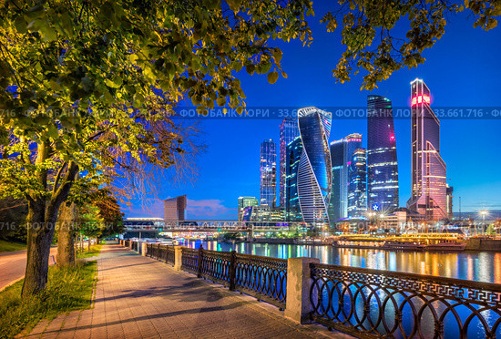 Ночной "Москва-Сити". Moscow City skyscrapers in a frame of green trees (2017 год). Редакционное фото, фотограф Baturina Yuliya / Фотобанк Лори