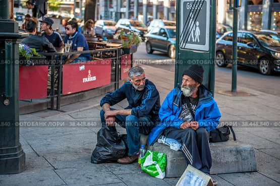 Norway, Oslo August 01 2013. Two elderly men ask for alms, sitting on the street in front of the cafe. The concept of indifference of the state to the poverty of people. Редакционное фото, фотограф Оксана Медведева / Фотобанк Лори