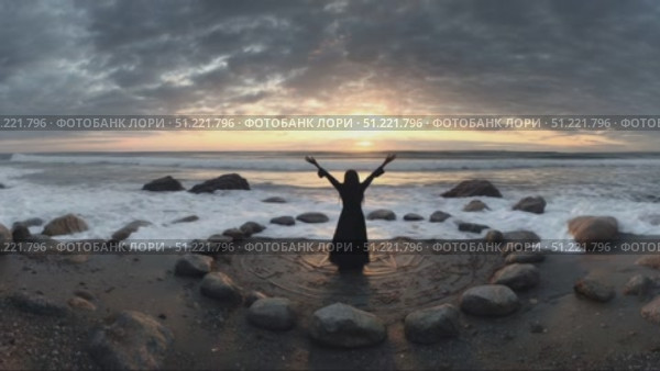 Ocean waves crash on the shore as a woman stands inside a stone circle on a beach, raising her arms towards the setting sun in a ritualistic pose. Стоковое AI-видео, аниматор Юрий Поздников / Фотобанк Лори