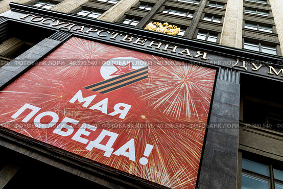 Огромный баннер с надписью "9 мая. Победа!" висит на фасаде Государственной Думы Российской Федерации в центре города Москвы, Россия (2023 год). Редакционное фото, фотограф Николай Винокуров / Фотобанк Лори