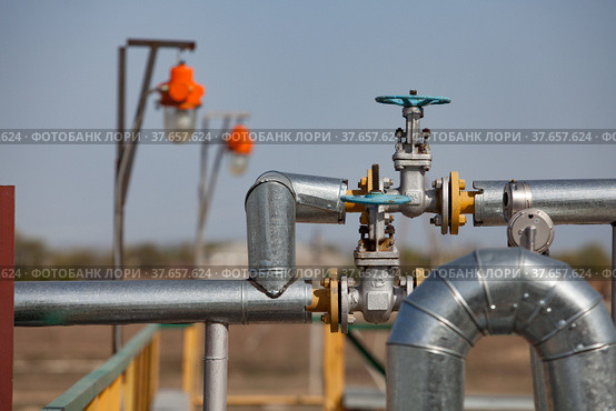 Oil refinery plant in desert. Valve armature and pipes on grey sky background. Focus on foreground. Стоковое фото, фотограф Alexey Rezvykh / Фотобанк Лори