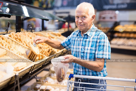 Old age senor examines bakery products in the grocery section of the supermarket. Стоковое фото, фотограф Татьяна Яцевич / Фотобанк Лори