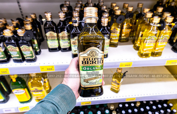 Оливковое масло Extra Virgin Filippo Berio в руке в супермаркете. Различные бутилированные оливковые масла. Редакционное фото, фотограф FotograFF / Фотобанк Лори