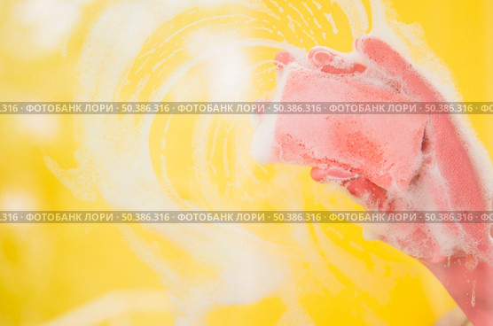 OLYMPUS DIGITAL CAMERA. close up hand wearing pink gloves washing yellow backdrop with sponge. Стоковое фото, агентство Ingram Publishing / Фотобанк Лори