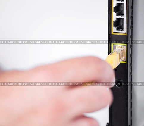 OLYMPUS DIGITAL CAMERA. hand plugging ethernet cable into router. Стоковое фото, агентство Ingram Publishing / Фотобанк Лори