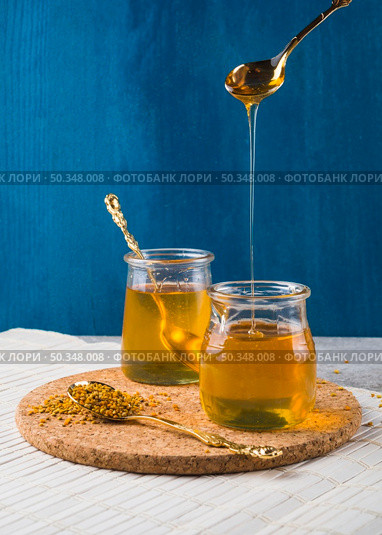 OLYMPUS DIGITAL CAMERA. honey dripping from spoon pot bee pollens cork coaster. Стоковое фото, агентство Ingram Publishing / Фотобанк Лори
