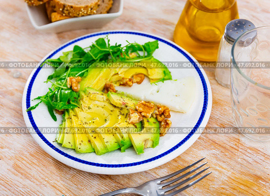 On table there is plate with snack - pieces of avocado pulp, walnut and arugula. Стоковое фото, фотограф Яков Филимонов / Фотобанк Лори