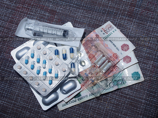 On the table are pills, capsules and ampoules with medicines, a syringe and Russian ruble bills. The bills say: "5000 ticket of the Bank of Russia" and "1000 Ticket of the Bank of Russia", on the ampoules: "Valid until:" Стоковое фото, фотограф Олег Тараканов / Фотобанк Лори