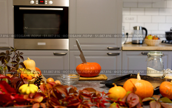 On the table is an orange pumpkin with a knife stuck in it. Kitchen. Стоковое фото, фотограф Alexandra Aleroewa / Фотобанк Лори