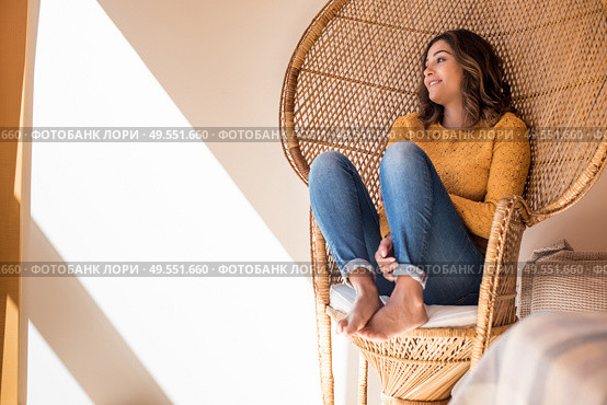 Optimistic woman sitting in a confortable rattan chair at home. Стоковое фото, агентство Ingram Publishing / Фотобанк Лори