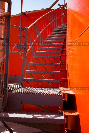 Orange steel storage tanks with acid and stairs on sulfuric (sulphuric) acid plant warehouse. Light blue sky background. Стоковое фото, фотограф Alexey Rezvykh / Фотобанк Лори
