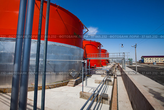 Orange steel storage tanks with acid on sulfuric acid (sulphuric) plant warehouse. Blue sky background. Kzylorda region, Kazakhstan. Стоковое фото, фотограф Alexey Rezvykh / Фотобанк Лори