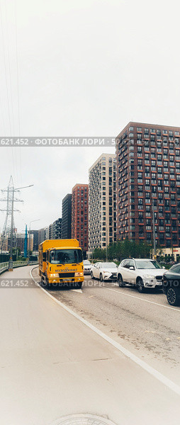 Оранжевая машина "Мосводоканала" стоит припаркованная вдоль дороги на фоне проезжающих мимо машин и красивых новостроек Москвы. Редакционное фото, фотограф Светлана Русских / Фотобанк Лори