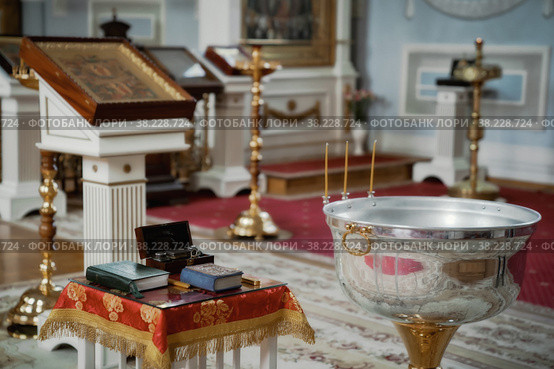 Orthodox church. Candles, cross, icon, prayer book, candles and Bible on table, baptismal font. Preparing for baptism of newborn child in Holy water. Sacrament of baptism. Стоковое фото, фотограф Aleksandr Golubev / Фотобанк Лори