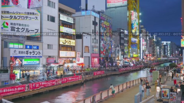 Osaka, Japan - Sep 22 2024, 4k, Panoramic view of Dotonbori river with a ship with tourists, a lot of people on embankment, there are a lot of advertising and illuminations on buildings, Osaka, Japan. Редакционное видео, видеограф Сергей Богомяко / Фотобанк Лори