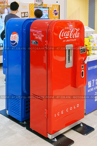 Osaka, Japan - Sep 25 2024, vertical, A close-up view of two antique soda machines, blue and red, Coca-Cola and Pepsi-Cola companies, in a shopping mall on Osaka Umeda, without people, Osaka, Japan. Редакционное фото, фотограф Сергей Богомяко / Фотобанк Лори