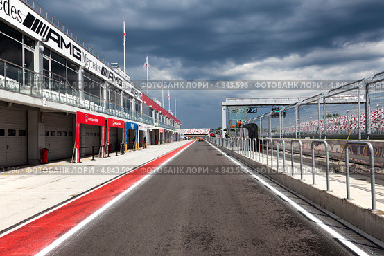 Освещенные солнцем питлейны подмосковной трассы Moscow Raceway на фоне грозового неба (2013 год). Редакционное фото, фотограф Николай Винокуров / Фотобанк Лори