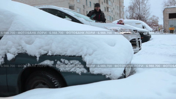 Отец с дочерью очищают автомобиль от снега на парковке во дворе. Стоковое видео, видеограф Кекяляйнен Андрей / Фотобанк Лори