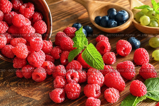 Overturned bowl with ripe raspberries on wooden table. Стоковое фото, фотограф Pixel_shot / Фотобанк Лори
