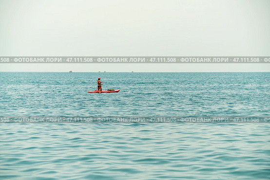 Paddleboarder Gliding Over Calm Water During a Serene Daytime Adventure. Стоковое фото, фотограф Roman Zavorotny / Фотобанк Лори